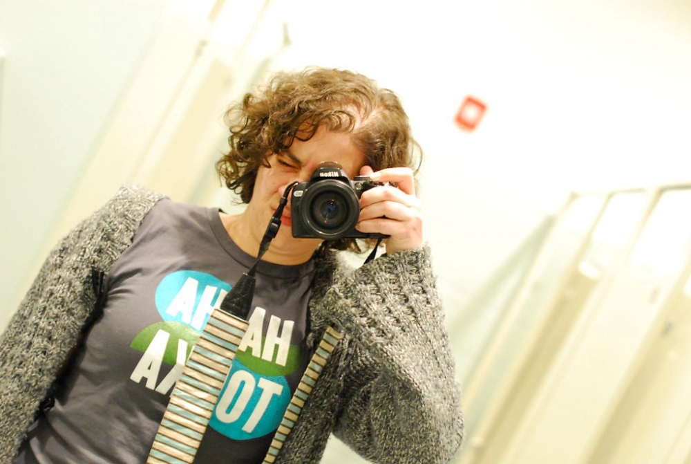a woman holding a camera to her face, taking a picture of herself in a mirror